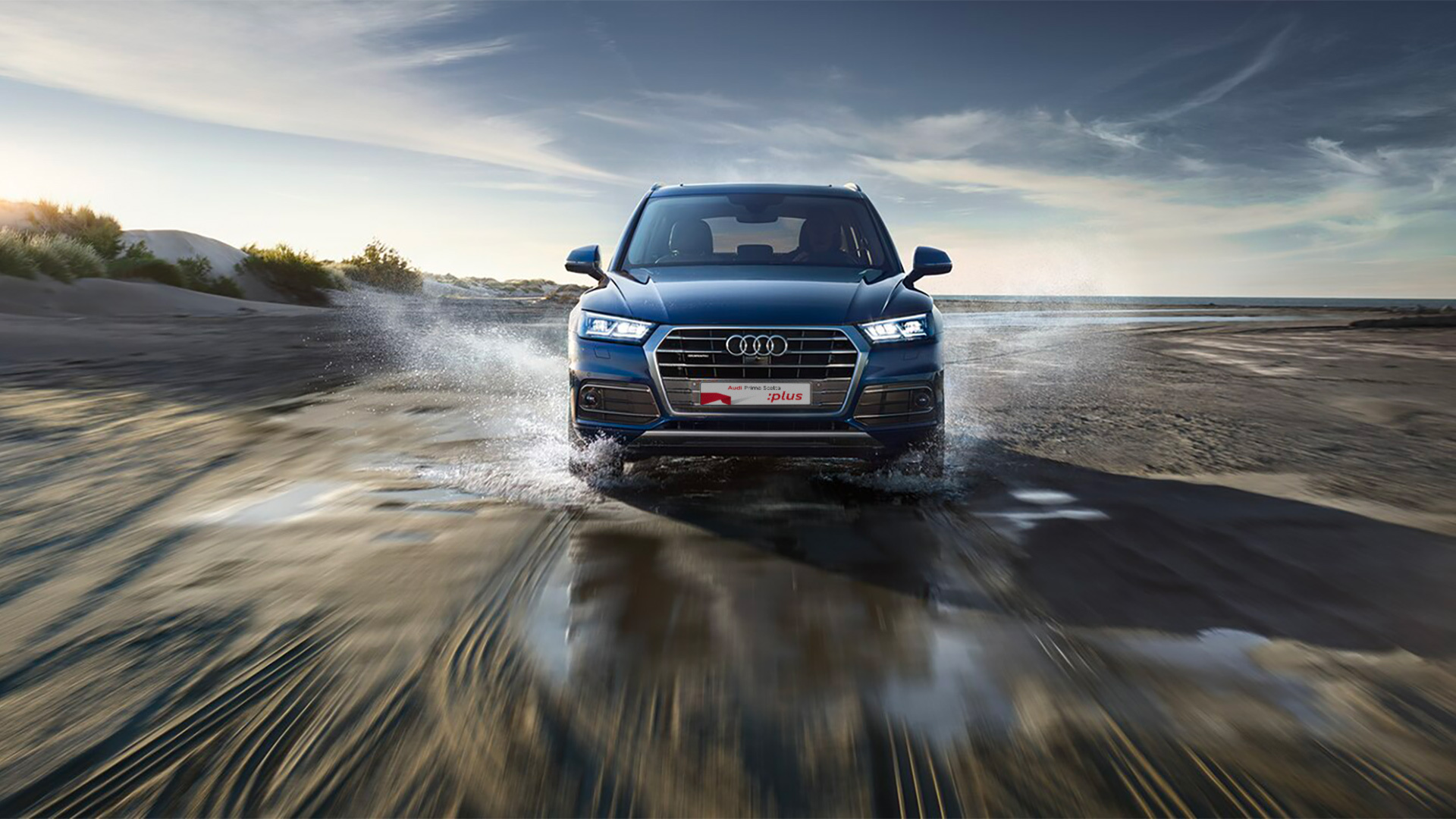 Audi Q5 che schizza acqua di una pozzanghera con la dicitura nella targa: Audi Prima Scelta :plus