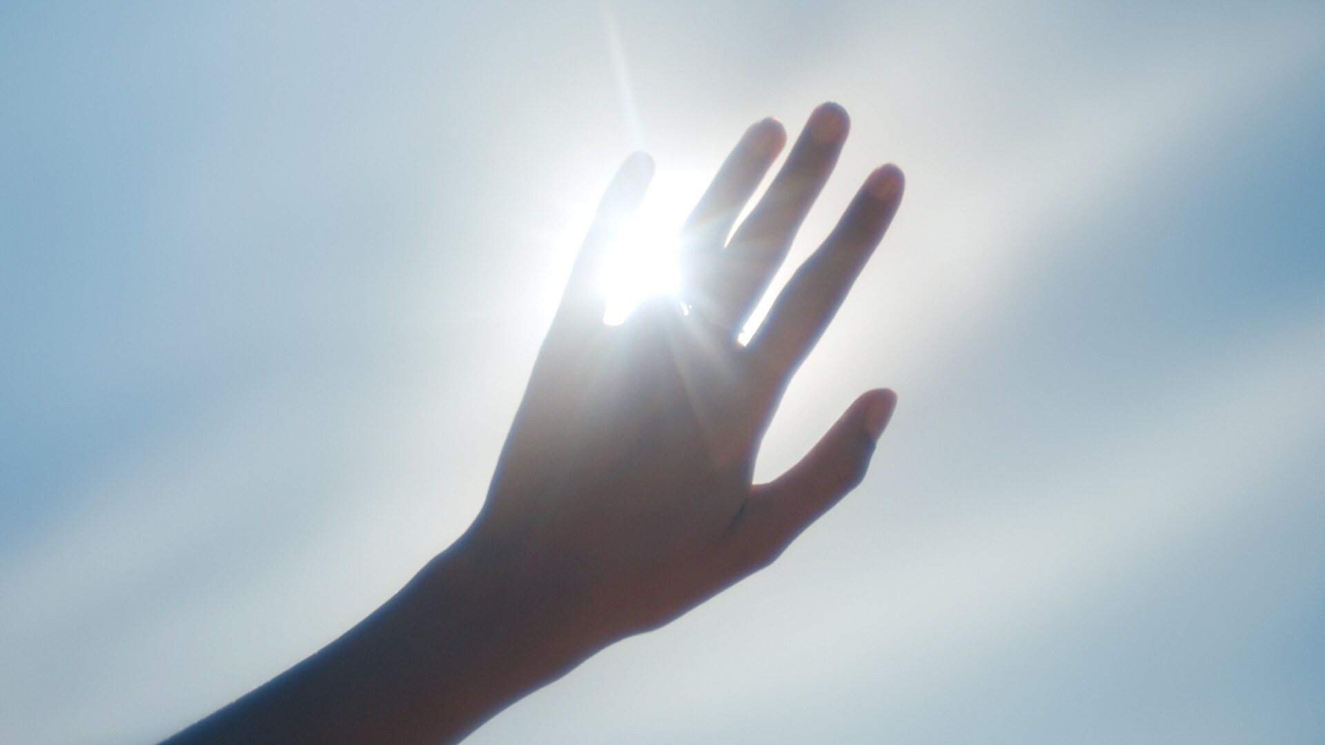 La luce del sole filtra tra le dita di una mano.